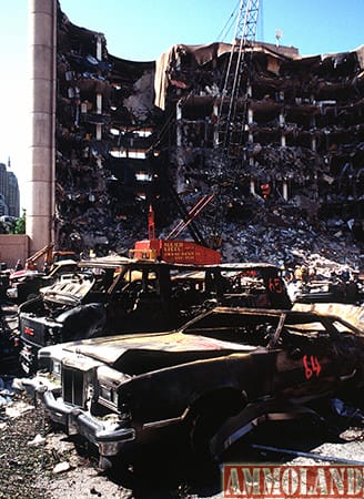 The bombed remains of automobiles with the bombed Federal Building in the background. The military is providing around the clock support since a car bomb exploded inside the building on Wednesday, April 19, 1995.