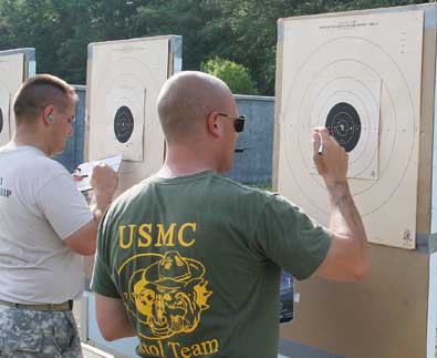 FORT BENNING, Ga.--A Soldier from the U.S. Marksmanship Unit and a member of the U.S. Marine Corps shooting team score their targets during the center fire individual match June 10 at Phillips Range on Fort Benning. The match was part of the 50th Interservice Pistol Championships, which brought the best shooters the military has to offer for a week of friendly competition and sharing of ideas. (Photo by Michael Molinaro, USAMU PAO)