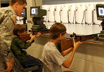 FORT BENNING, Ga.--Spc. David Sprecher, U.S. Army Marksmanship Unit, answers questions from Mackenzy Crawford (right), 14, Columbus, Ga. as Glenn Fausti (left), 13, Columbus, fires his rifle at Pool Indoor Range. The two youngsters are among 52 kids who make up the Fort Benning Junior Rifle Club, instructed by members of the USAMU International Rifle team. (Photo by Michael Molinaro, USAMU PAO)