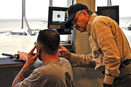 FORT BENNING, Ga.--Ray Arrendondo, coach of the U.S. Army Marksmanship Unit's International Pistol team, gives some instruction to Sgt. Robert Price, Warrior Transition Unit, Brooke Army Medical Center, San Antonio, Texas, Mar. 31 at Pool Indoor Range. Price was among a group of Wounded Warriors from the Army who came to Fort Benning and the USAMU to train in Air Pistol and Rifle in preparation for the Warrior Games to be held in May. (Photo by Michael Molinaro, USAMU PAO)