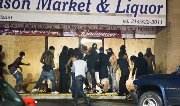 Rioters loot the Ferguson Market and Liquor store on August 16, 2014 in Ferguson, Missouri. Several businesses were looted as police held their position nearby.