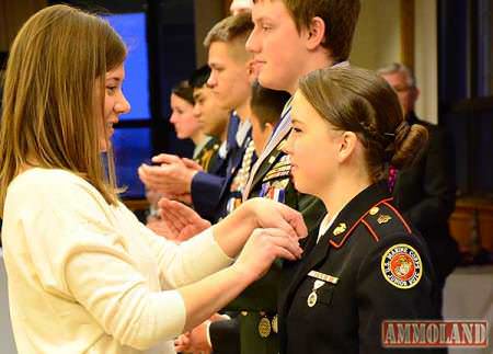 Katie Harrington pinning new Junior Distinguished marksmen at CMP air rifle events