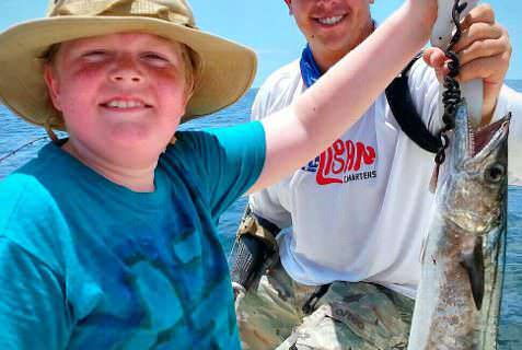 Bobby Dove helps Isaac Hill hold up his first kingfish in the Gulf of Mexico.