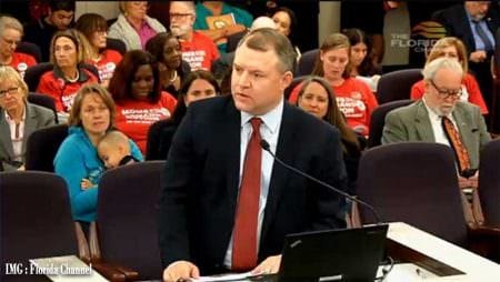 Fake Paid Moms Demand Action Protesters earn their days pays, behind State Sen. Rob Bradley, R-Fleming Island, as he addresses the Senate Judiciary Committee on Jan. 24, 2017