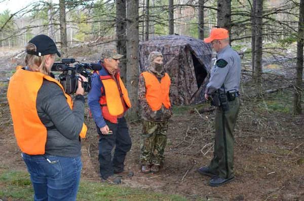 From left, videographer Kristin Ojaniemi; Paul Theriault and his grandson Andrew Stahl, both of Petoskey; and Michigan Department of Natural Resources Conservation Officer Mark Leadman. Leadman talks with deer hunters Theriault and Stahl in Marquette County during the firearm deer season in November 2016, while Ojaniemi captures the scene for the “Wardens” television show.
