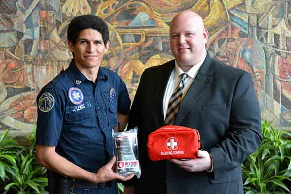 Janick Lewis, New Orleans EMS Medical Coordinator at the New Orleans Ernest N. Morial Convention Center, presents a Bleeding Control Kit to Brett Slocum, Assistant Director of Public Safety, New Orleans Ernest N. Morial Convention Center.