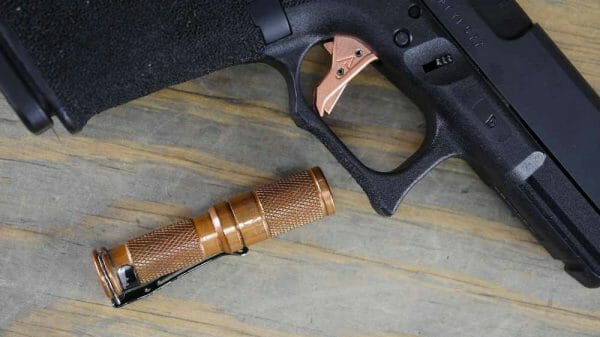 My Glock 19C Gen 4 with the Agency Arms Liberty Trigger installed next to a copper Maratac AAA flashlight.