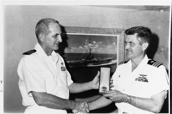 Navy Cmdr. James B. Stockdale is presented with the Distinguished Flying Cross by Capt. Bartholomew J. Connolly III, commanding officer of USS Oriskany, Aug 13, 1965.