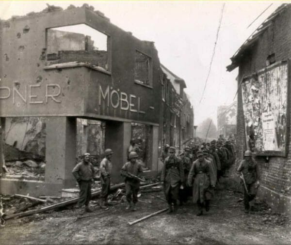 U.S. Army soldiers with the 117th Infantry Regiment, 30th Infantry Division and 2nd Armored Division usher captured German troops near the Siegfried Line in Palenburg, Germany, Oct. 1, 1944.