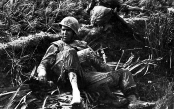 A unit from Battalion Landing Team 1/4 establishes a night defensive position in the middle of a broad expanse of muddy rice paddies in Vietnam during Operation Deckhouse VI in 1967. The Marine in the foreground has obtained a non-issue rifle, which rests against a pack on the ground.