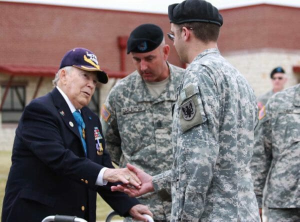 Army Col. James Lamar Stone, a Medal of Honor recipient, hands a challenge coin to Army 1st Lt. Joshua Nichols of the 90th Aviation Support Battalion. Stone was at the ceremony that named the unit's facility after him, Nov. 6, 2011.