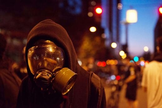 Seattle May Day a protester wearing a gas mask is pushed back by the Police in downtown at twilight, iStock-523756389