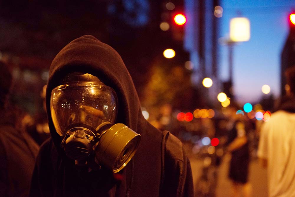 Seattle May Day a protester wearing a gas mask is pushed back by the Police in downtown at twilight, iStock-523756389