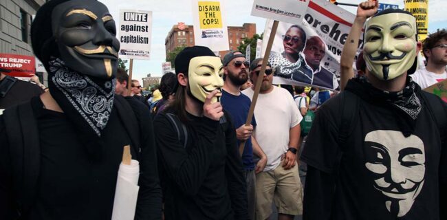 Cleveland, Ohio, USA - July 17, 2016: Protesters wearing masks associated with the Occupy Wall Street movement participate in the "Shut Down Trump and the RNC March" the day before the Republican National Convention officially began. The event was organized to protest racism, islamophobia, attacks on immigrants and members of the LBGTQ community, the one percent and endless war. iStock-583851226