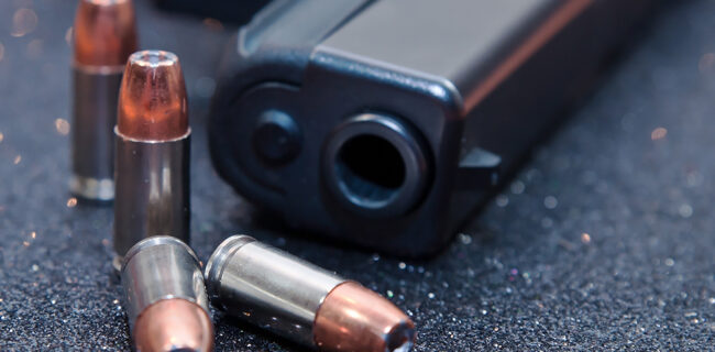 Four hollow point 9mm bullets with a black pistol. iStock-944927240