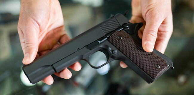 Gunsmith shop assistant demonstrates black pistol in hands stock photo iStock-1398682785
