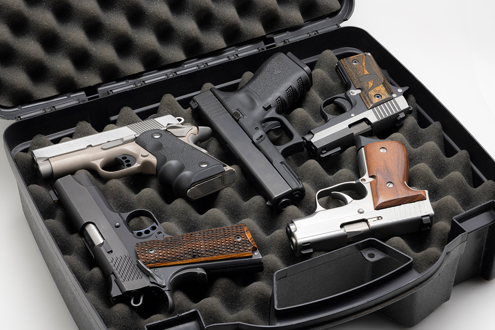 Handgun collection in a plastic hard case on white background. iStock-1357038188