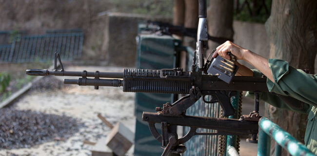 A man is preparing an M60 rifle down a shooting range. iStock-611295580