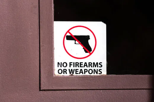 No firearms or weapons sign on the glass entrance door to the business establishment. iStock-1295573667