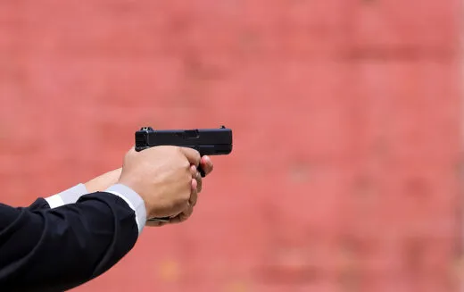 Close up view of hand holding a pistol / handgun taking aim for target. iStock-1175500022