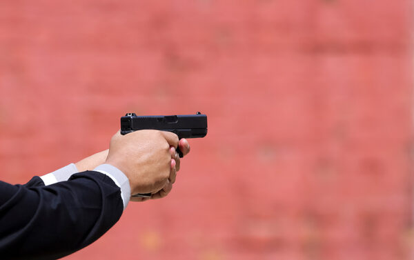 Close up view of hand holding a pistol / handgun taking aim for target. iStock-1175500022