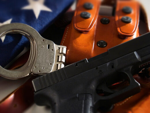 Police handgun symbolizing anti-gun states arming non-citizen officers while restricting citizens’ gun rights