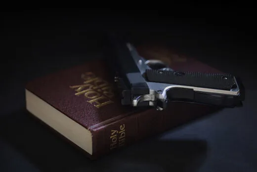 Bible and a concealed carry handgun representing Christian self-defense and Second Amendment rights iStock-1505706481