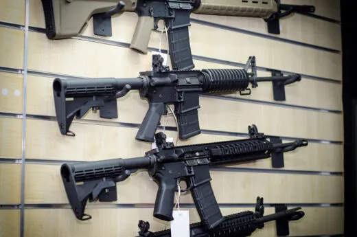 Gun store wall with AR-15 style rifles for sale.