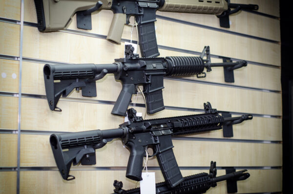Gun store wall with AR-15 style rifles for sale.